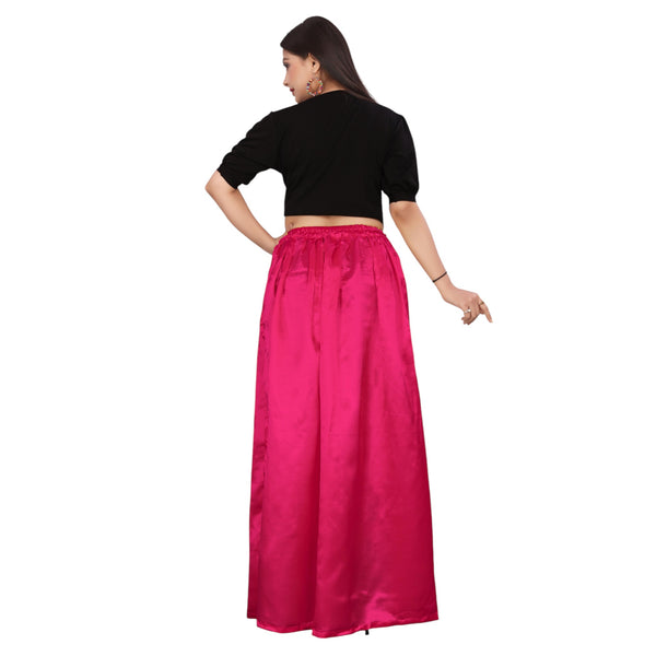 A woman modeling a deep pink, satin side cut belly dance skirt with side slits, paired with a black top.