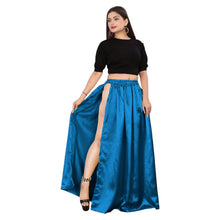 A woman modeling a royal blue satin belly dance skirt with side slits, paired with a black top and black heels.